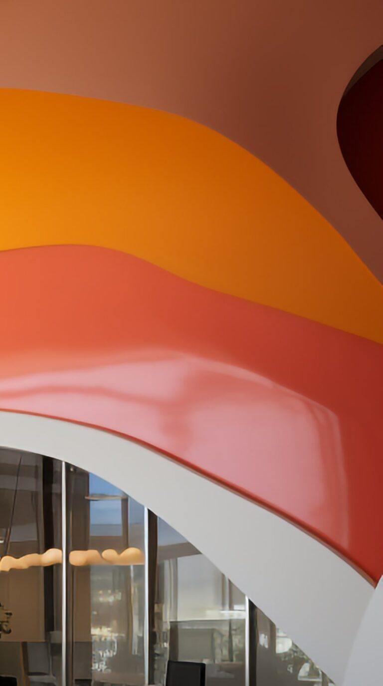 A massive, gracefully arched wall adorned with alternating vibrant orange and crisp white stripes.